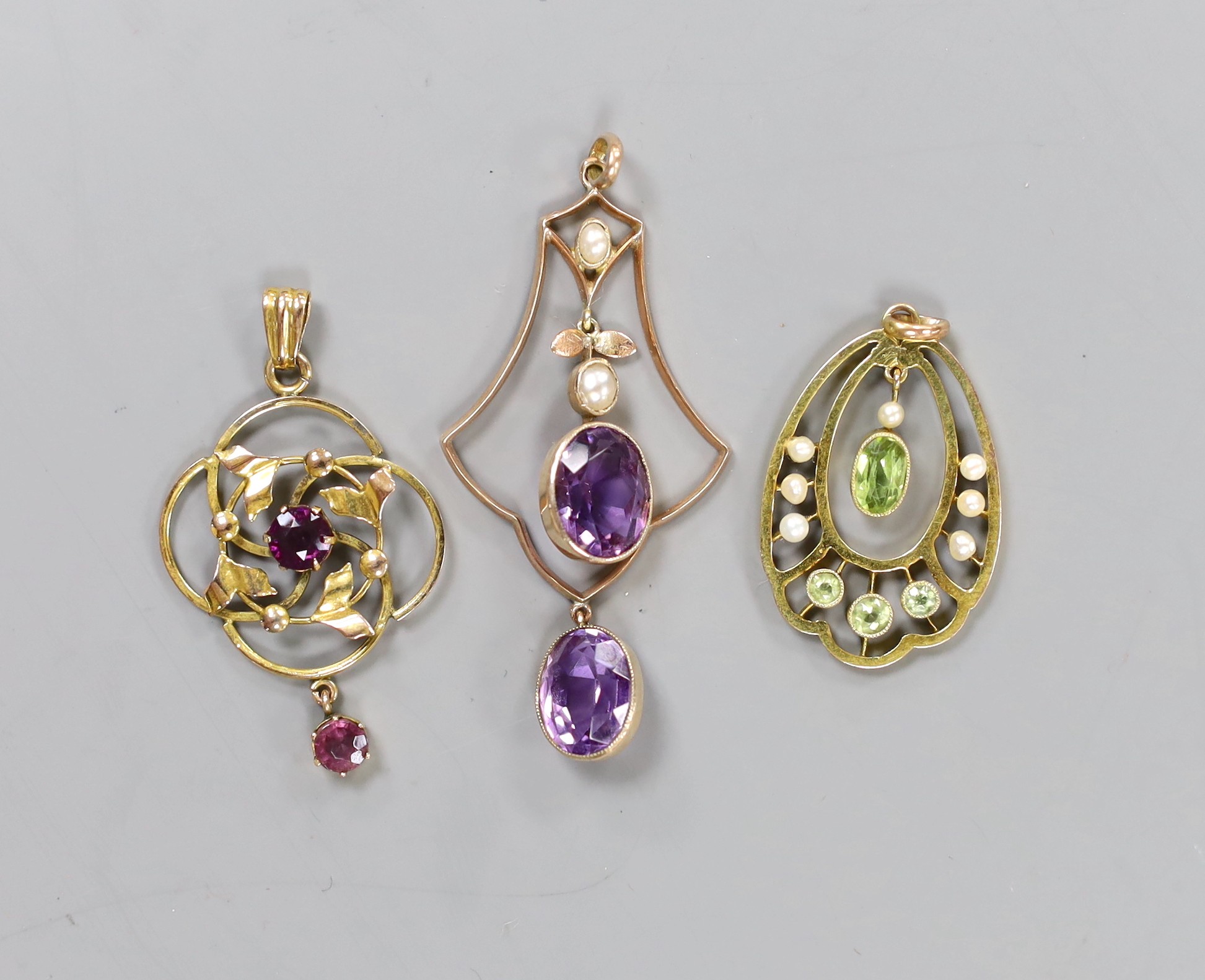 Three assorted yellow metal and gem set drop pendants including a 9ct, peridot and seed pearl, 33mm, gross weight 8 grams.